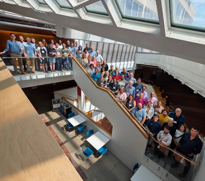 A large group of mathematicians and math educators standing on an open staircase in the Harvard Science Center.