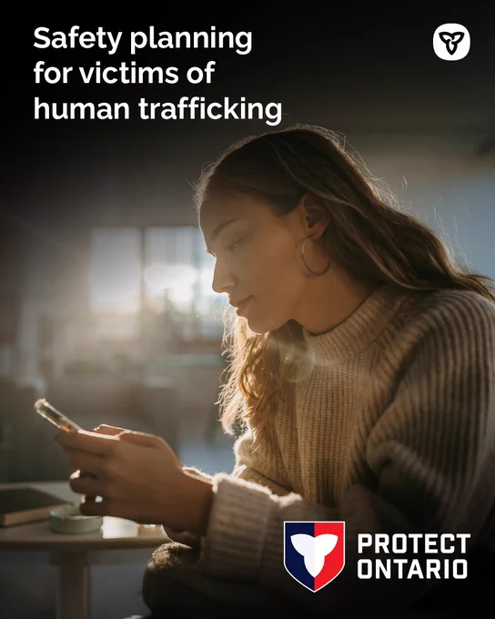 Young woman reading her phone; poster headline "Safety planning for victims of human trafficking"
