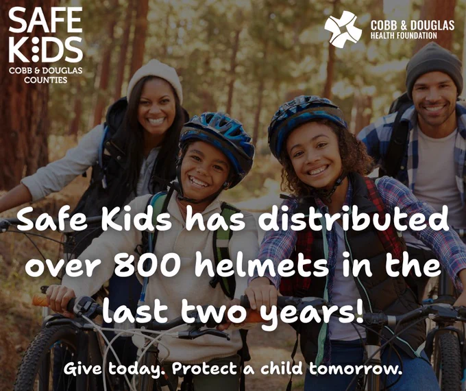 Four children wearing helmets and riding bikes in a wooded area promoting Safe Kids' helmet distribution efforts.