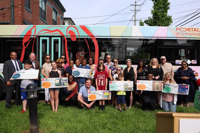 Students and adults pose for a photo in front of a TARC bus. 