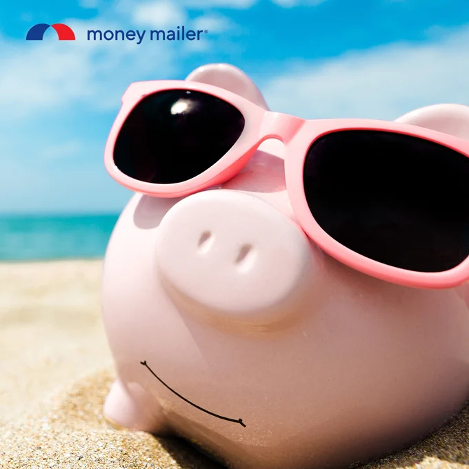 Pink piggy bank wearing oversized pink sunglasses on a sunny sandy beach with blue sky and ocean in the background.