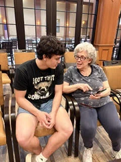 Bay High School Tech Club at Normandy Senior Living facility, with a student and a resident seated.