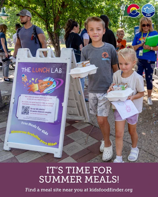 Children carrying meal boxes and smiling near a sign for 'The Lunch Lab,' promoting free summer meals for kids. The scene includes trees and several people in the background. Logos for Colorado and the Colorado Department of Education are visible. The text at the bottom reads: 'It's time for summer meals! Find a meal site near you at kidsfoodfinder.org.