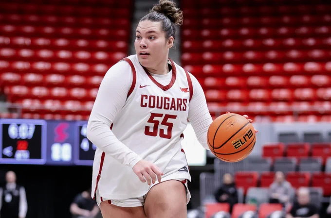 a WSU basketball player in a white uniform with crimson "Cougars" lettering and a number 55 plays basketball, a basketball in hand