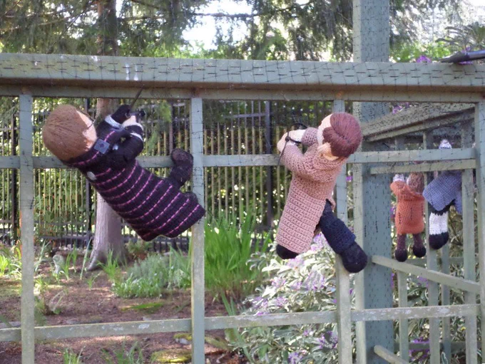 Crochet dolls of Vinsher Grath & Marshal Kahler hanging from the lattice fence, zip tying the deer net under the top 2x4. Nathaniel Sackett & Robert Townsend plus yard in background. 