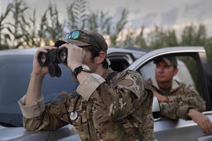 A BOSTAR agent looking through binoculars.