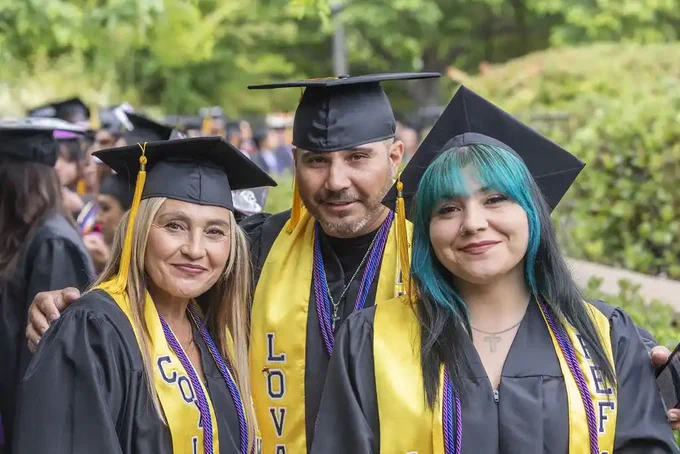 Three students in black graduation caps and gowns at 2025 commencement