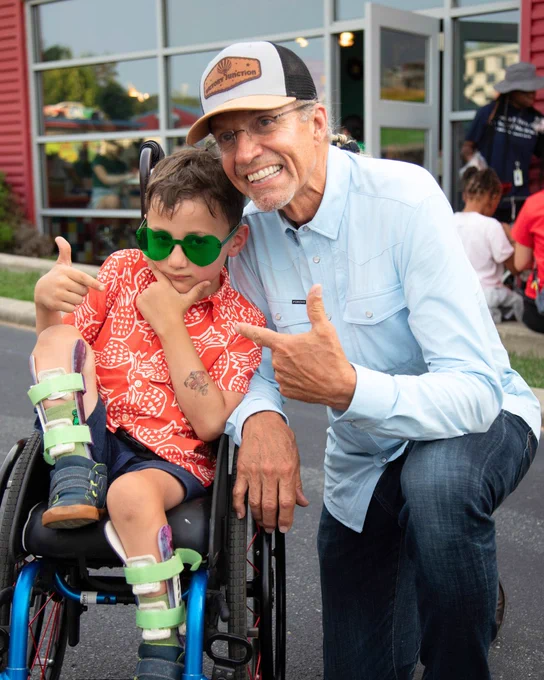 A Camper and Kyle Petty posing and smiling for the camera in front of the pit stop.