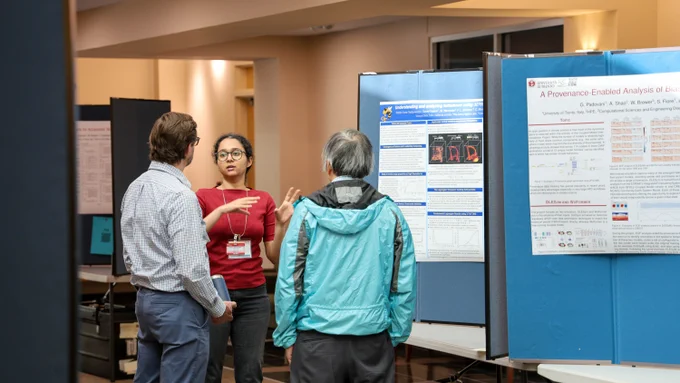 A researcher presents scientific findings to attendees gathered around a poster display during the 2026 Oak Ridge Leadership Computing Facility User Summit.