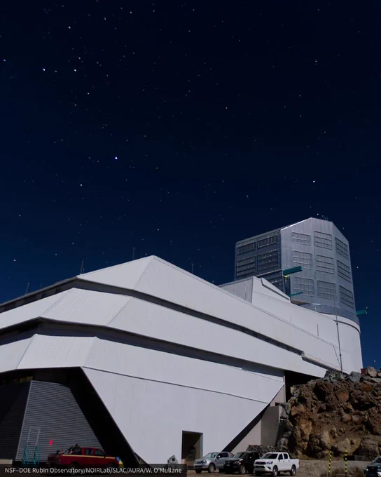 Large angular white observatory on a rocky site under a clear and deep blue night sky. 