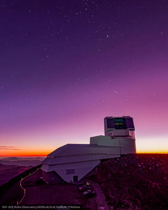 Boot-shaped white observatory with open, angular dome under a pink twilight sky and stars sprinkled throughout.