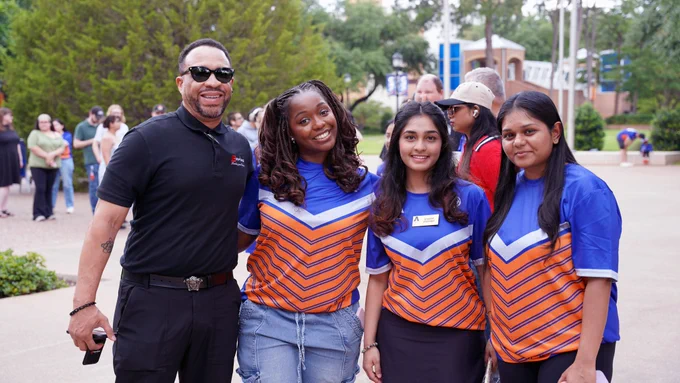 Pictured is a photo of four people posing for a group photo at the UTA Libraries Family Day and Picnic that was held of the Library Mall. 