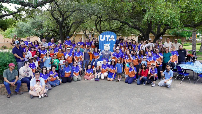 Pictured is a group of the UTA Libraries staff members with the university mascot Blaze who is sitting in a large chair.