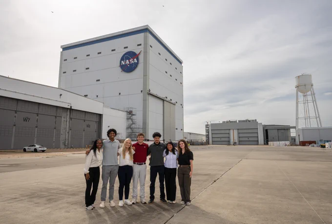 7 interns pose for a photo outside of the Vertical Assembly Building at NASA's Michoud Assembly Facility. Credit: NASA/Steven Seipel
