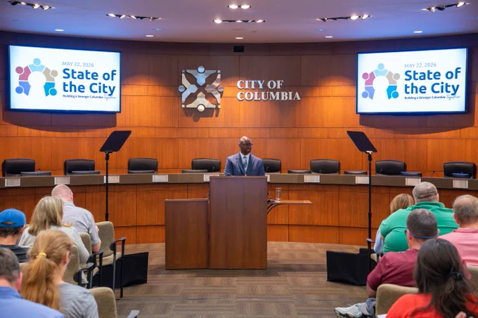 City of Columbia official delivering the State of the City address to an audience in a formal chamber.