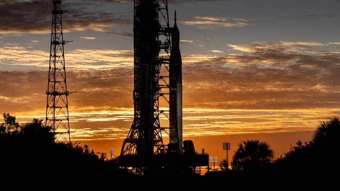 Clouds and the sun illuminate the sky on Wednesday, Jan. 28, 2026, as NASA’s Artemis II SLS (Space Launch System) rocket and Orion spacecraft stand vertical at Launch Complex 39B at NASA’s Kennedy Space Center in Florida. Credit: NASA/Cory Huston