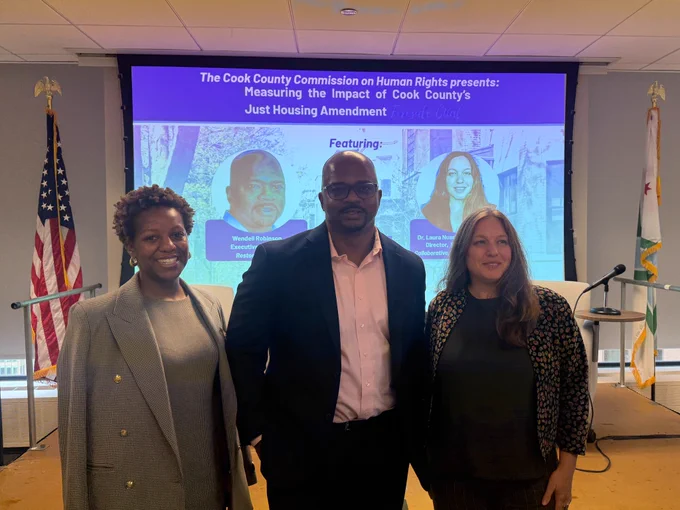 Executive Director of the Department of Human Rights and Ethics, Jennifer King, wearing a dress and blazer, stands beside Mr. Wendell Robinson who is wearing a suit and pink collared shirt. Dr. Laura Nussbaum-Barberena stands at the end wearing a blazer.