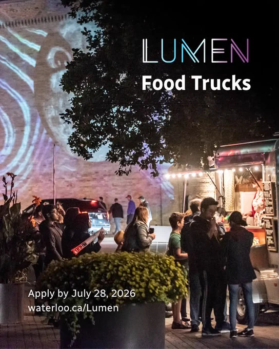 A night scene featuring a group of people gathered at a food truck with a light projection on a nearby building wall with text overlay that reads, "LUMEN Food Trucks. Apply by July 28, 2026 waterloo.ca/Lumen."