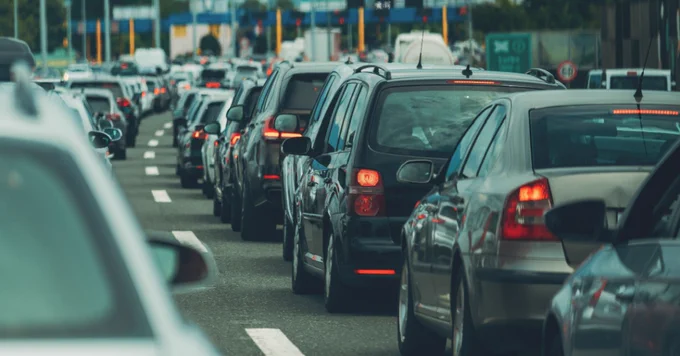 Heavy traffic on a multi-lane highway with numerous cars closely packed together.