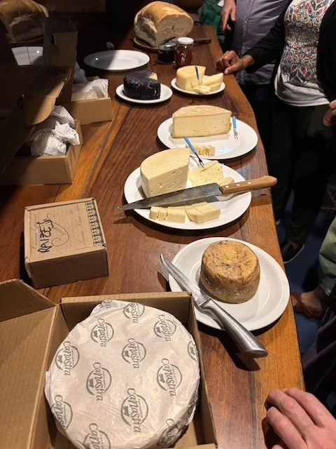 A wooden table with different kinds of cheese cut and displayed