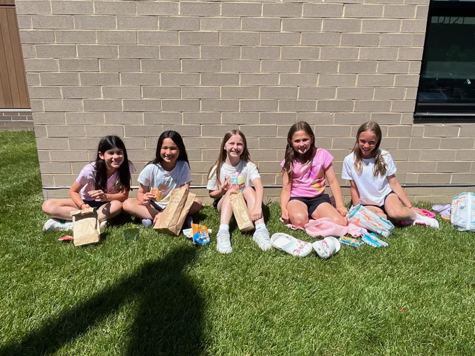 students smile while eating lunch outside
