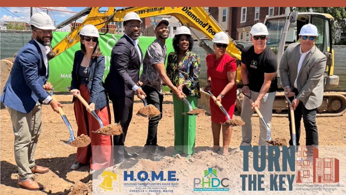 group of smiling people holding shovels on dirt lot