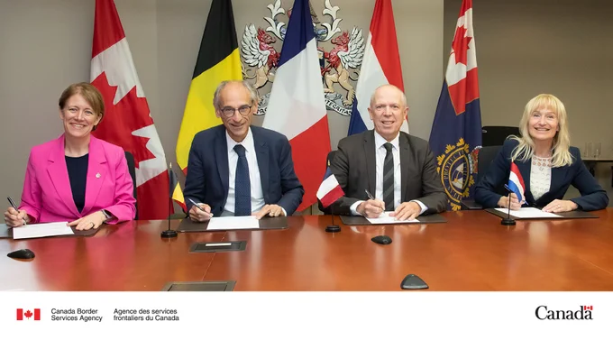 Representatives from the customs administrations of Canada, Belgium, France and the Netherlands signing a Letter of Intent to combat international drug trafficking. Pictured from left to right: Erin O’Gorman, President of the Canada Border Services Agency; Kristian Vanderwaeren, Administrator General of Customs and Excise Belgium; Benoit Godart, Head of International Affairs for Customs of the French Republic, and Nanette Van Schelven, the Director General of the Customs Administration of the Netherlands. The flags of each country are displayed in the background.