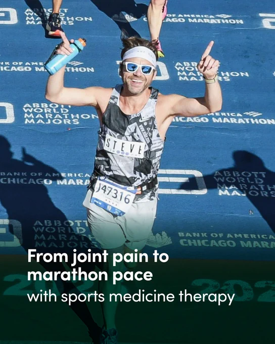 A person running and smiling on the marked course of the Bank of America Chicago Marathon, with arms raised and holding a water bottle. They are wearing a patterned tank top and sunglasses. The ground has visible logos and event names. Text over the image reads: "From joint pain to marathon pace with sports medicine therapy.