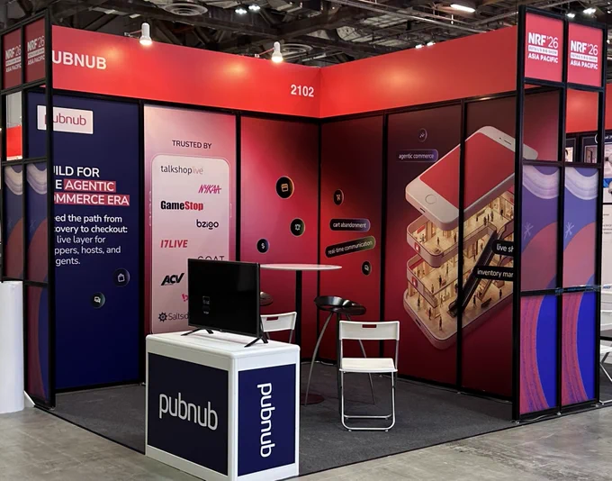 A vibrant booth display for the company PubNub at a tech conference, emphasizing their presence and partnerships in the e-commerce industry. The booth features a mix of digital and physical elements, creating an engaging atmosphere.