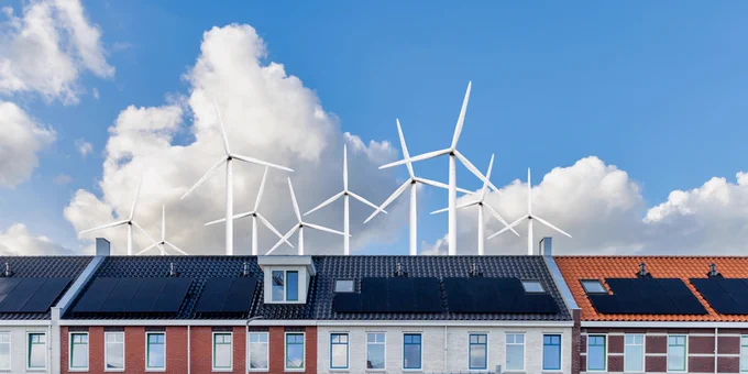A row of houses with wind turbines in the background. Stock photo. 