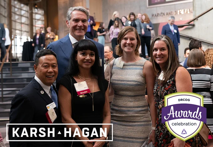 A group of five people stand and smile together inside a crowded reception area. The logos for Karsh Hagan and the DRCOG awards celebration are overlayed below them.