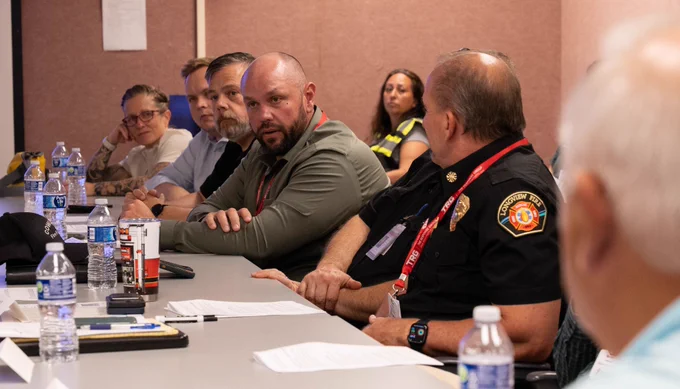 Individuals seated at table, including individual in Longview Fire uniform