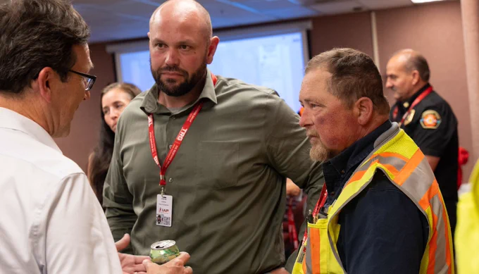 Bob speaking to 2 individuals, including individual in safety vest