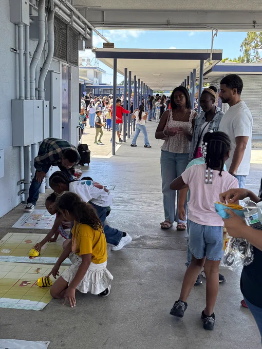Students from 186th Street Elementary School playing robotics activity while parents watch