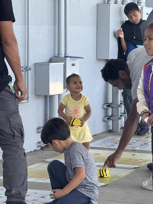 Students from 186th Street Elementary School playing robotics activity while parents watch