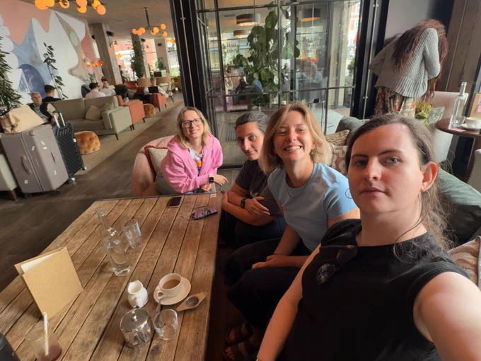 Selfie photo of Hannah and the attendees on a sofa at the venue.