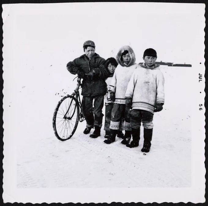 Four youths, one with a bicycle, Nunavut, July 1956