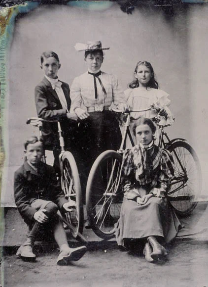Five individuals posing with two bicycles