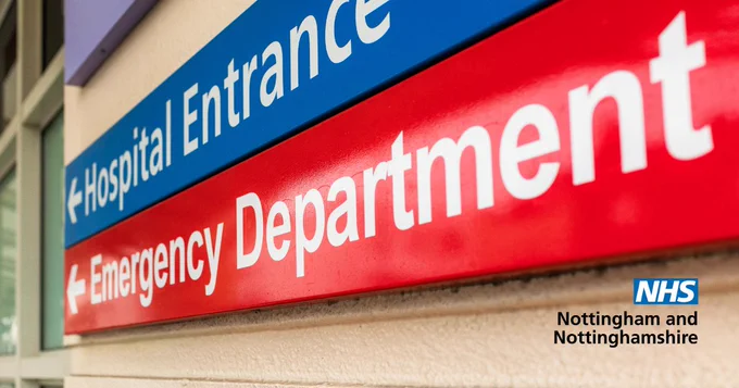 Close-up of a hospital sign showing “Emergency Department” in white text on a red background, with a blue sign above pointing to the “Hospital Entrance.” NHS Nottingham and Nottinghamshire logo visible in the corner.