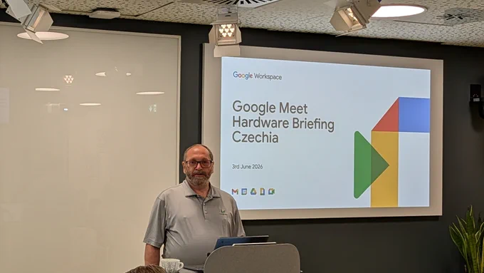 A photo of a man standing at the front of the room. He is facing an audience and behind him is his first slide, on which are the words “Google Meet Hardware Briefing Czechia” and the date of the event, 3rd June 2026.