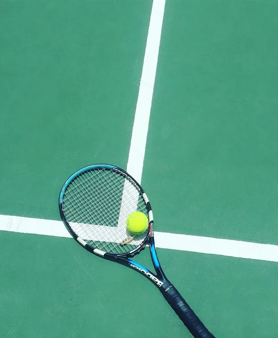 A tennis racket and a ball on a tennis court. 
