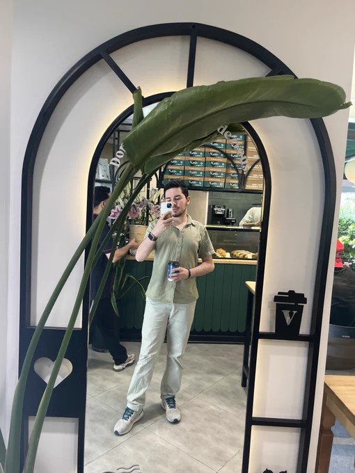 Man wearing green taking a selfie infrint of a mirror