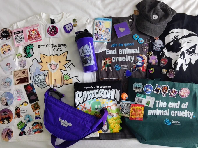 Collection of items including stickers, t-shirts, bags, and acrylic charms.