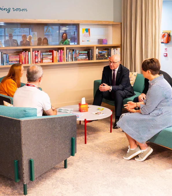 First Minister John Swinney sitting around a table and speaking to people at SAMH's The Nook