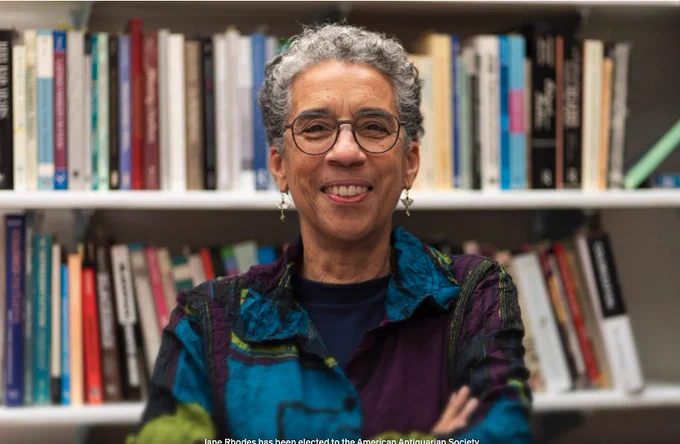 Jane Rhodes in front of a bookshelf filled with academic books.