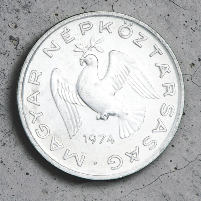 Pièce de monnaie en argent ornée d’un oiseau tenant une plante dans son bec.