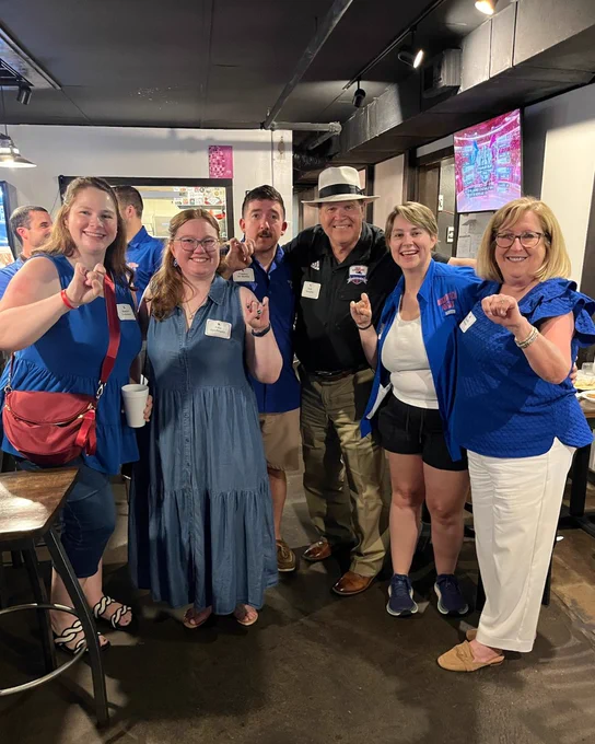 A group of Louisiana Tech alumni form the bulldog symbol with their hands while smiling