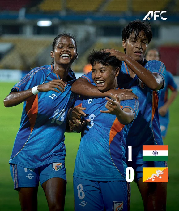 The India women's football team celebrates their victory over Bhutan with smiling faces and joyful camaraderie on the field.