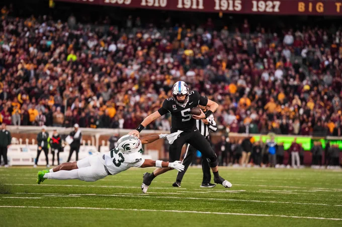 Drake Lindsey's stiff arm against Michigan State in 2025 wearing a white helmet and black uniform. 