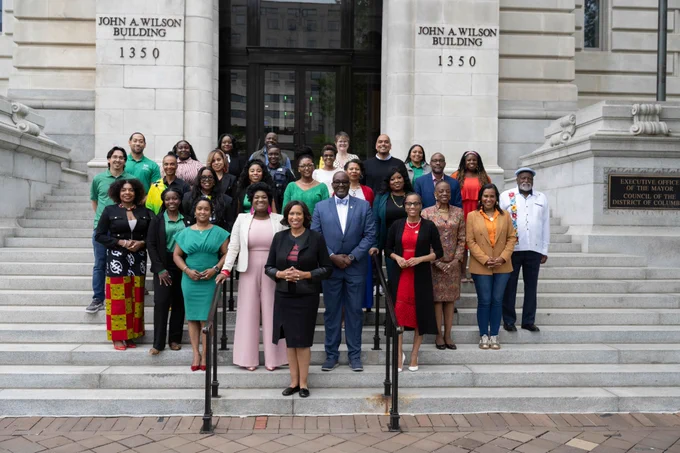Mayor Bowser stands on the steps of the John A. Wilson Building with members of her administration who identify as Caribbean. 